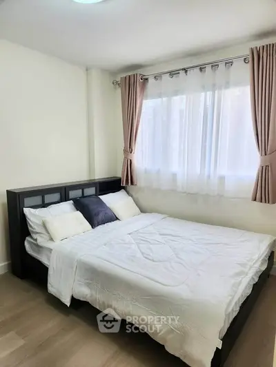 Cozy bedroom with large window and elegant curtains, featuring a comfortable bed and stylish decor.