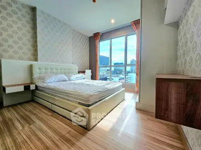 Spacious bedroom with modern decor and city view, featuring large windows and elegant furnishings.