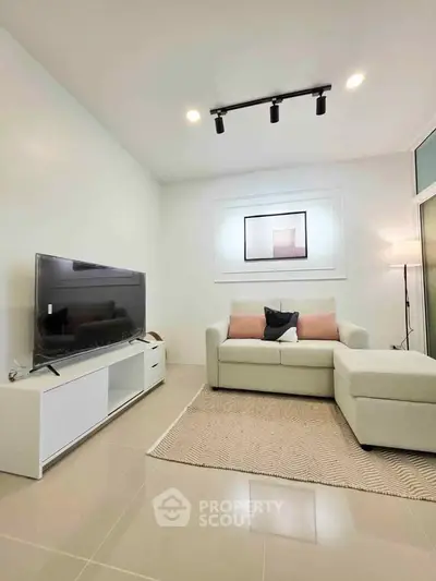 Modern living room with sleek furniture and large TV, perfect for relaxation and entertainment.