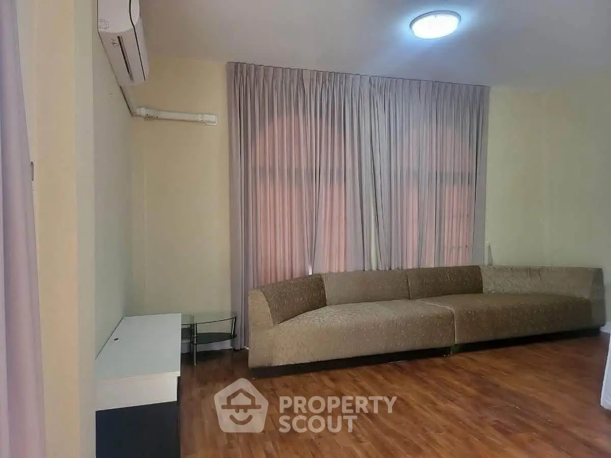 Spacious living room with elegant sofa and wooden flooring, perfect for relaxation and entertainment.