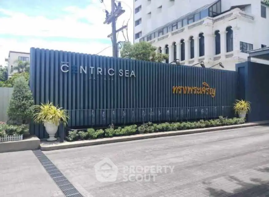 Modern building entrance with stylish signage and lush landscaping.