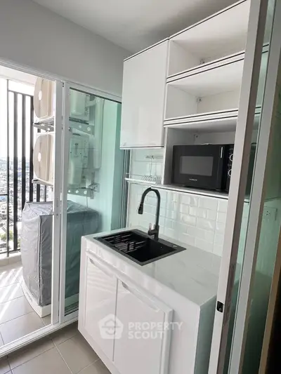 Modern compact kitchen with sleek white cabinetry and balcony view