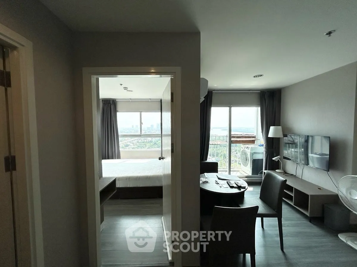 Modern apartment with open living room and bedroom, featuring a stunning city view.