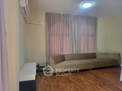 Spacious living room with elegant sofa and wooden flooring, perfect for relaxation and entertainment.