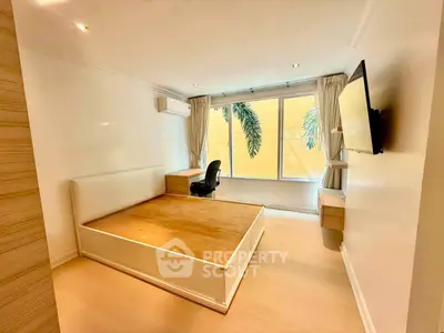 Spacious bedroom with large window and modern furnishings in a bright apartment.