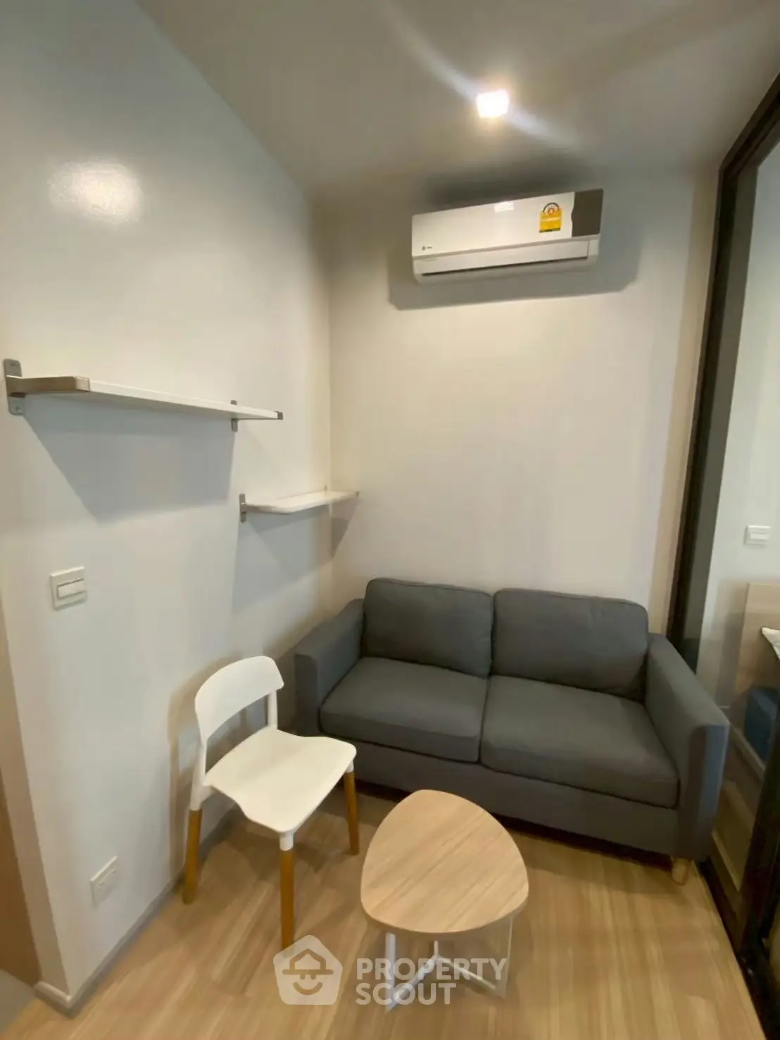 Cozy living room with modern sofa, air conditioning, and stylish wooden flooring.