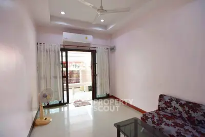 Spacious living room with ceiling fan and air conditioning, featuring a glass door leading to a balcony.