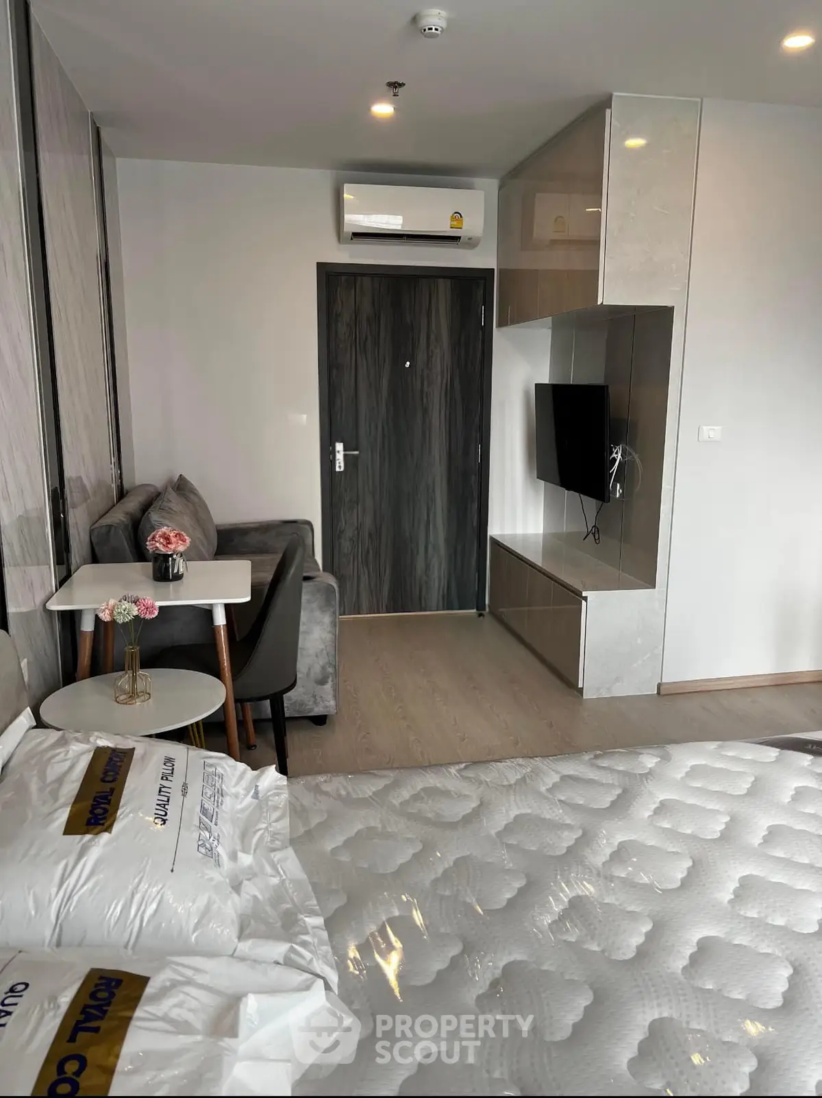 Modern studio apartment with stylish decor and compact living space, featuring a cozy sofa and wall-mounted TV.