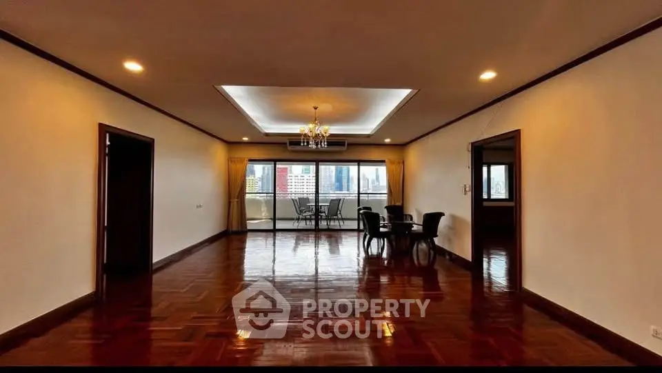 Spacious living room with elegant chandelier and city view balcony.