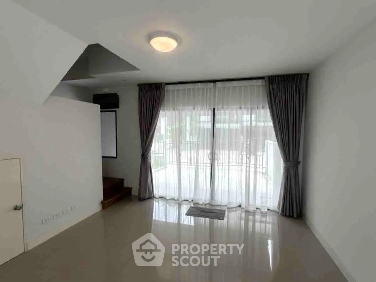 Spacious living room with large windows and elegant curtains, perfect for natural light and modern living.