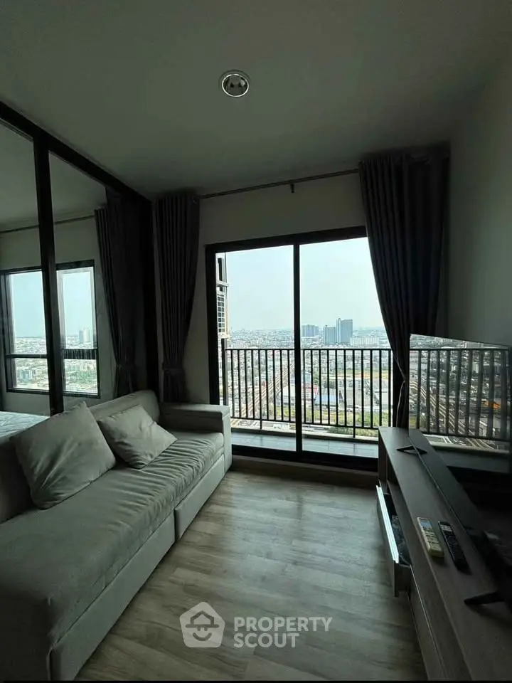 Modern living room with stunning city view from large window, featuring cozy sofa and sleek TV setup.