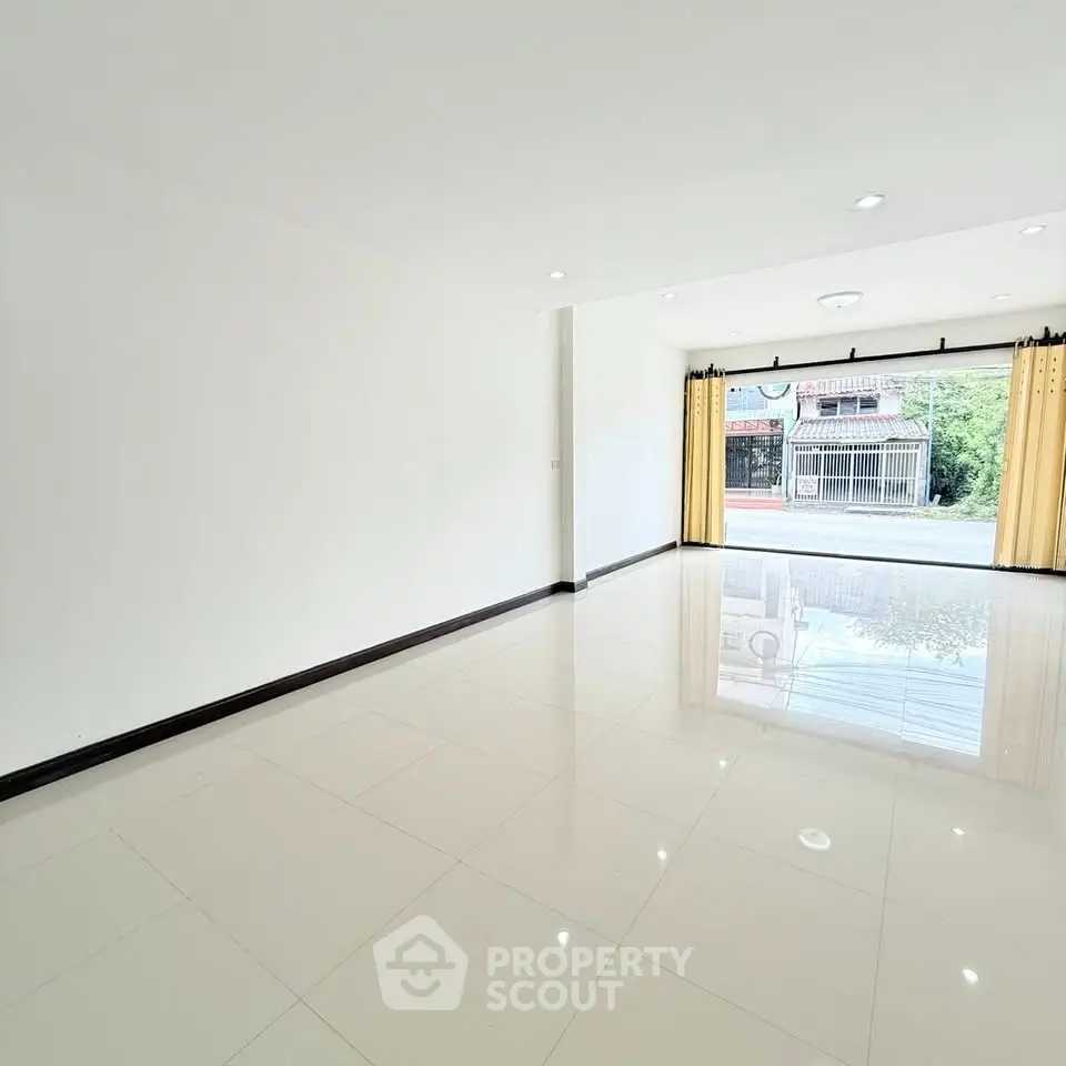 Spacious open-plan living area with large windows and glossy tiled floors.