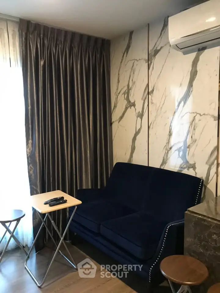 Stylish living room with elegant marble walls and plush blue sofa, perfect for modern comfort.