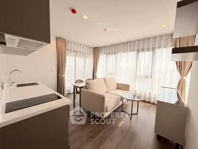 Modern living room with open kitchen and large windows offering city views.