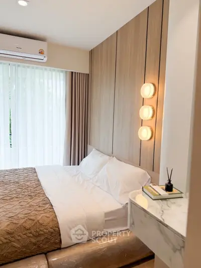 Modern bedroom with stylish lighting and elegant decor, featuring a cozy bed and natural light through large windows.