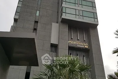 Modern high-rise building exterior with sleek design and lush greenery.