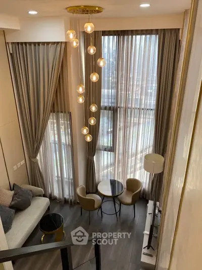 Luxurious high-ceiling living room with elegant chandelier and floor-to-ceiling windows.