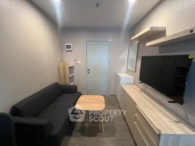 Modern living room with sleek furniture and wall-mounted TV in a cozy apartment.