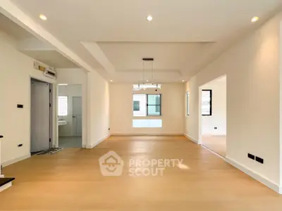Spacious open-plan living area with modern lighting and wooden flooring.