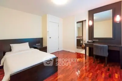 Spacious bedroom with elegant wooden flooring and modern furniture