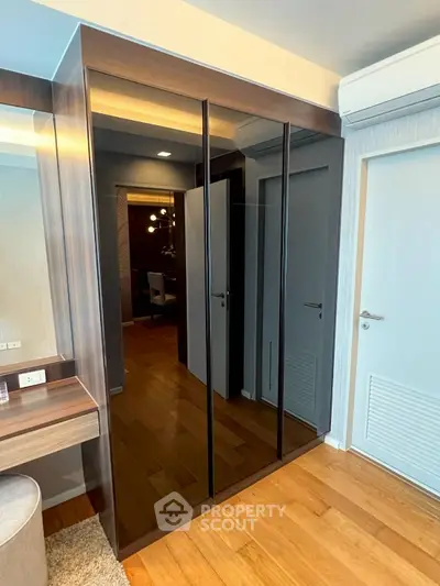 Modern bedroom with sleek mirrored wardrobe and wooden flooring