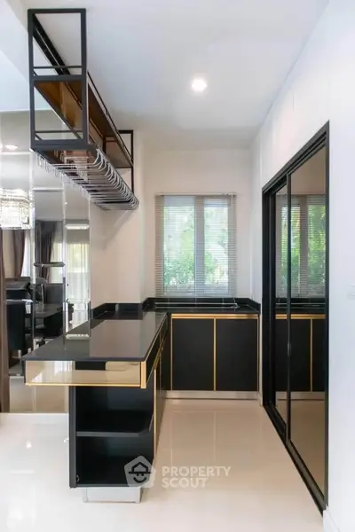Modern kitchen with sleek black cabinetry and open shelving, featuring a large window for natural light.