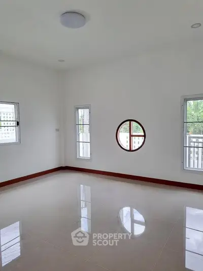 Spacious empty room with unique round window and glossy tiled floor