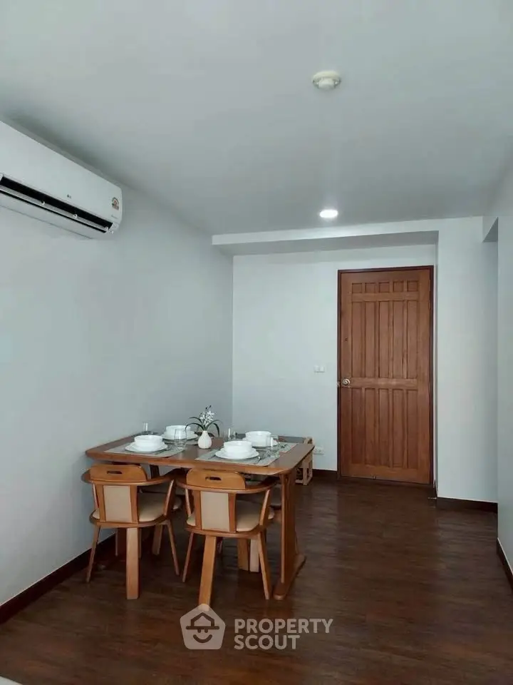 Cozy dining area with wooden table and chairs, featuring modern air conditioning and elegant decor.