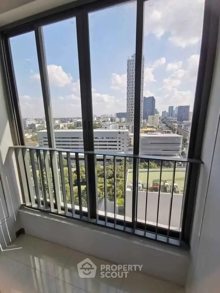Stunning city view from a modern high-rise apartment window, showcasing urban skyline and lush greenery.
