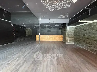 Spacious commercial interior with modern flooring and stone accent walls, ideal for retail or office space.
