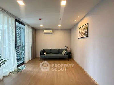 Modern living room with sleek sofa and balcony access, featuring elegant wooden flooring and stylish decor.