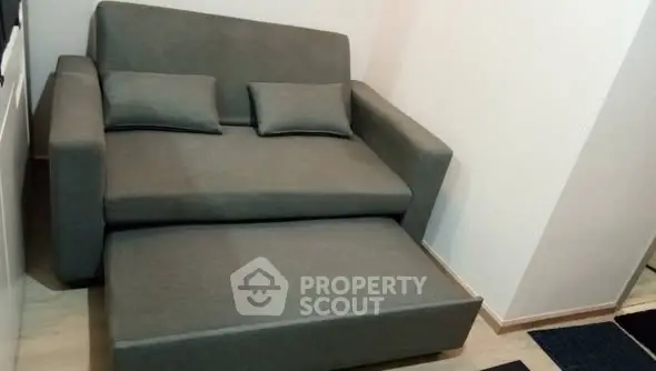 Compact gray sofa bed in a cozy living room corner, perfect for small spaces.