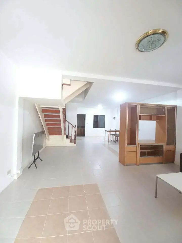 Spacious open-plan living area with modern staircase and stylish furniture.