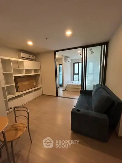 Modern living room with sleek furniture and open view to bedroom