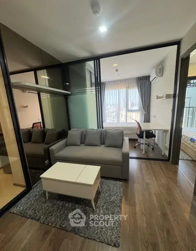 Modern living room with glass partitions and cozy furniture in a stylish apartment.