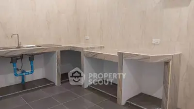 Modern kitchen with marble countertops and tiled flooring, featuring a sleek sink and ample workspace.