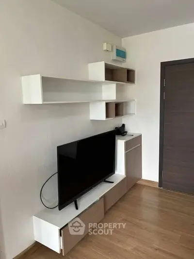 Modern living room with sleek TV unit and wall shelves in minimalist design.