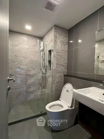 Modern bathroom with sleek design, featuring a glass shower enclosure and contemporary fixtures.