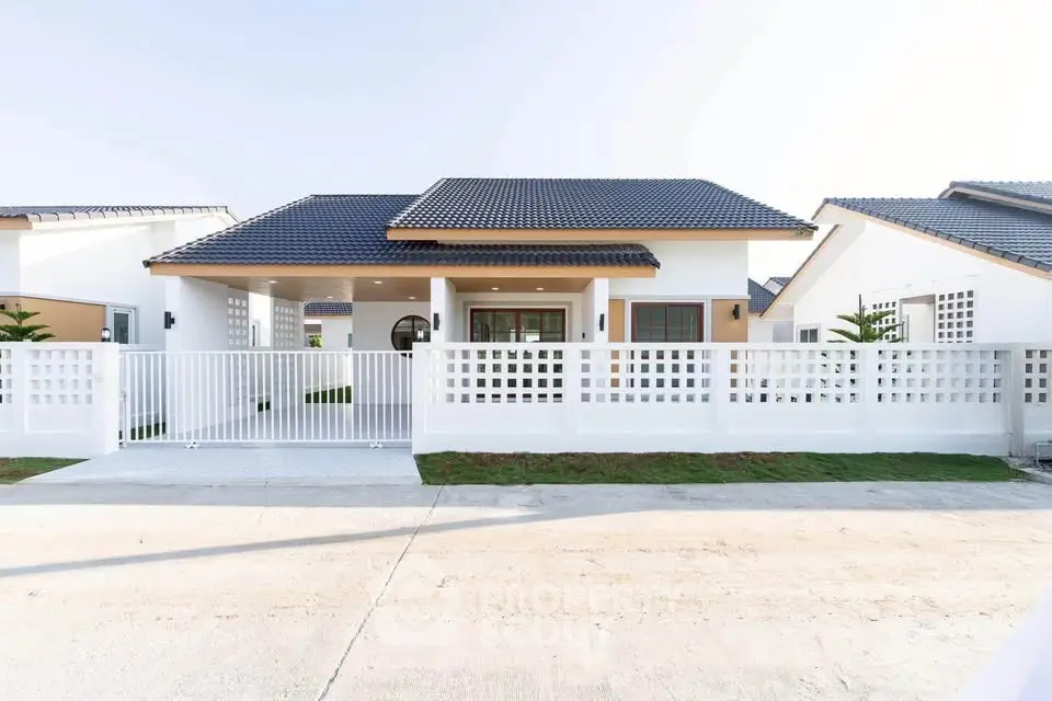 Modern single-story house with white facade and gated entrance in a serene neighborhood.