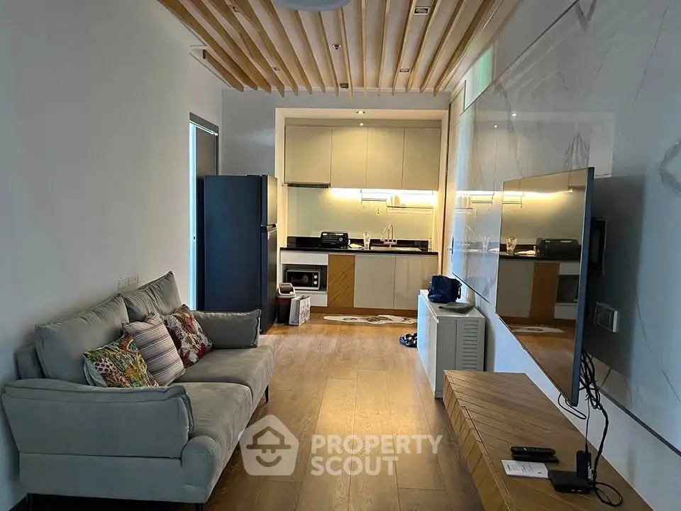 Modern living room with open kitchen, stylish decor, and wooden flooring in a cozy apartment.