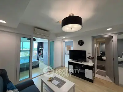 Modern living room with open view to bedroom and bathroom, featuring sleek decor and natural light.