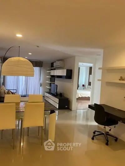 Modern open-plan living room with dining area and study desk, featuring sleek furniture and ambient lighting.