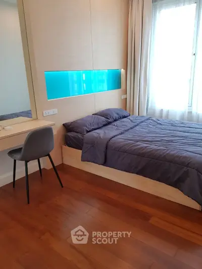 Modern bedroom with wooden flooring and stylish furniture in a bright apartment