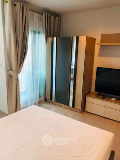 Modern bedroom with sleek wardrobe and TV, featuring elegant curtains and neutral tones.