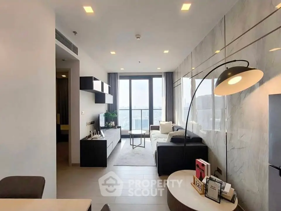 Modern living room with stylish decor and large window offering city views.