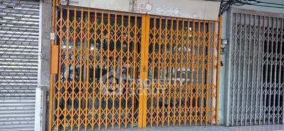 Secure commercial property with robust metal gate in urban setting, ideal for retail or storage use.