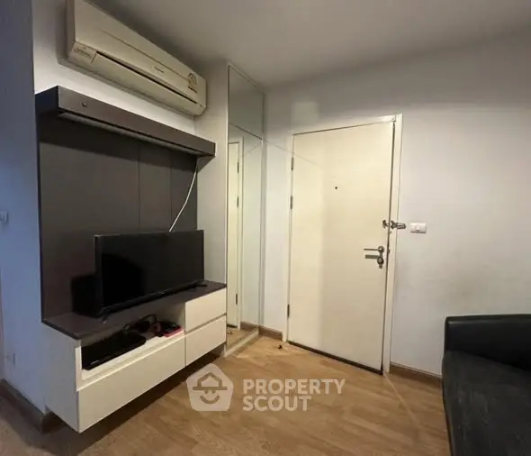 Modern living room with TV and air conditioning, featuring sleek wooden flooring.