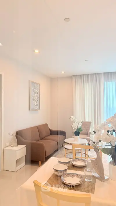Elegant living room with cozy seating and dining area, featuring modern decor and natural light.