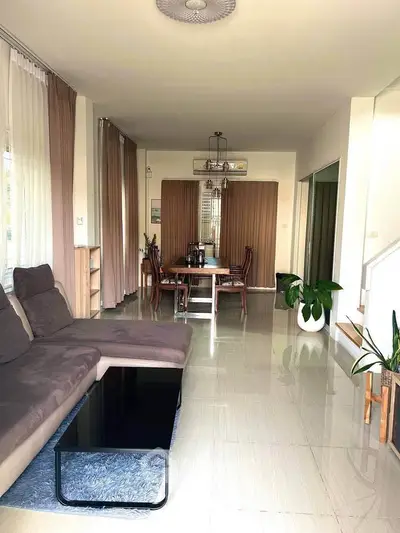 Spacious living room with modern decor and dining area, featuring large windows and elegant furnishings.
