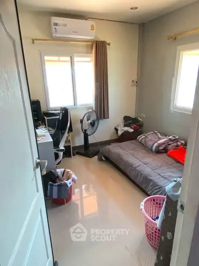 Cozy small bedroom with single bed, desk, and air conditioning, ideal for compact living.